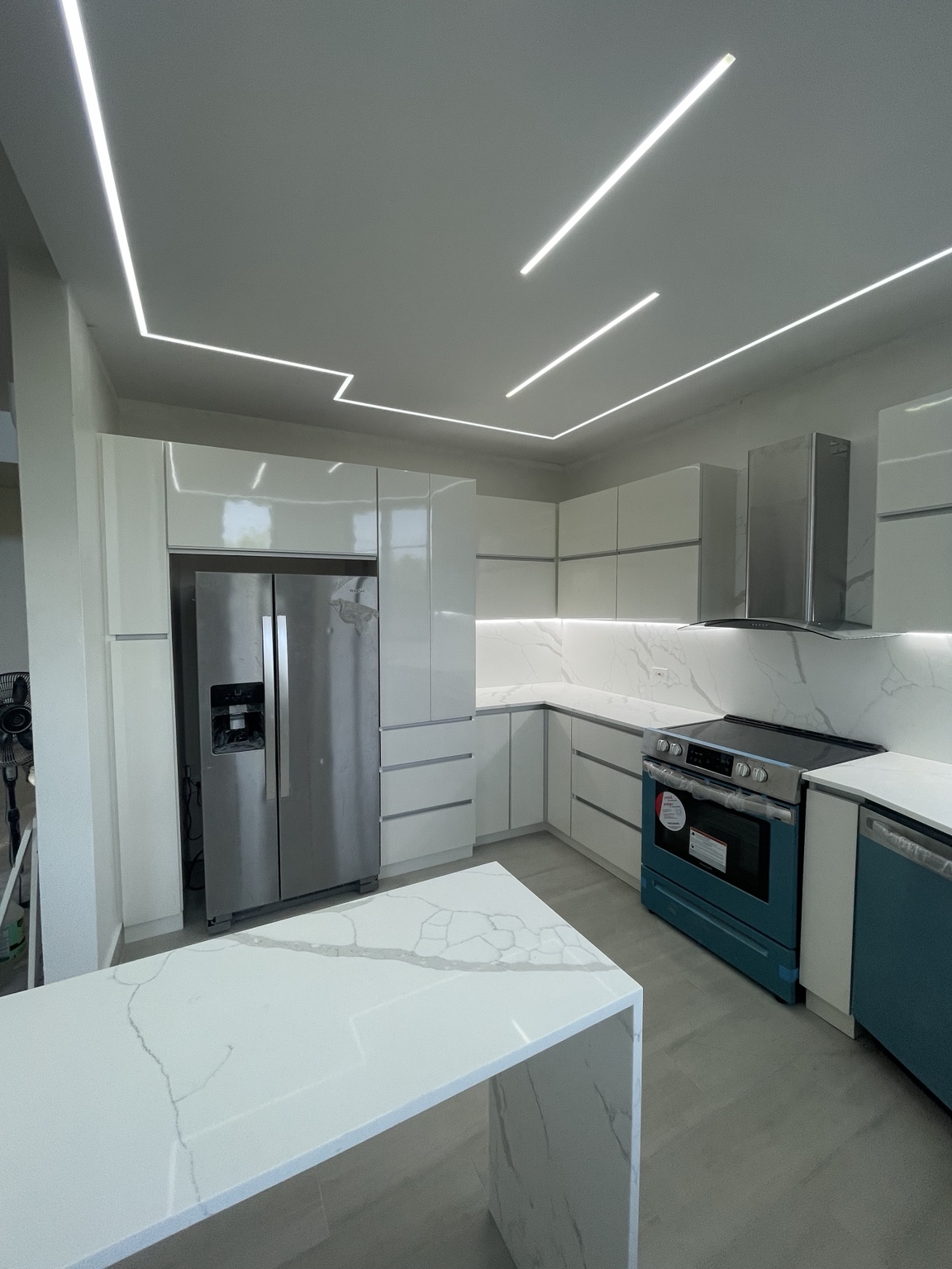 Cocina blanca minimalista con iluminación lineal