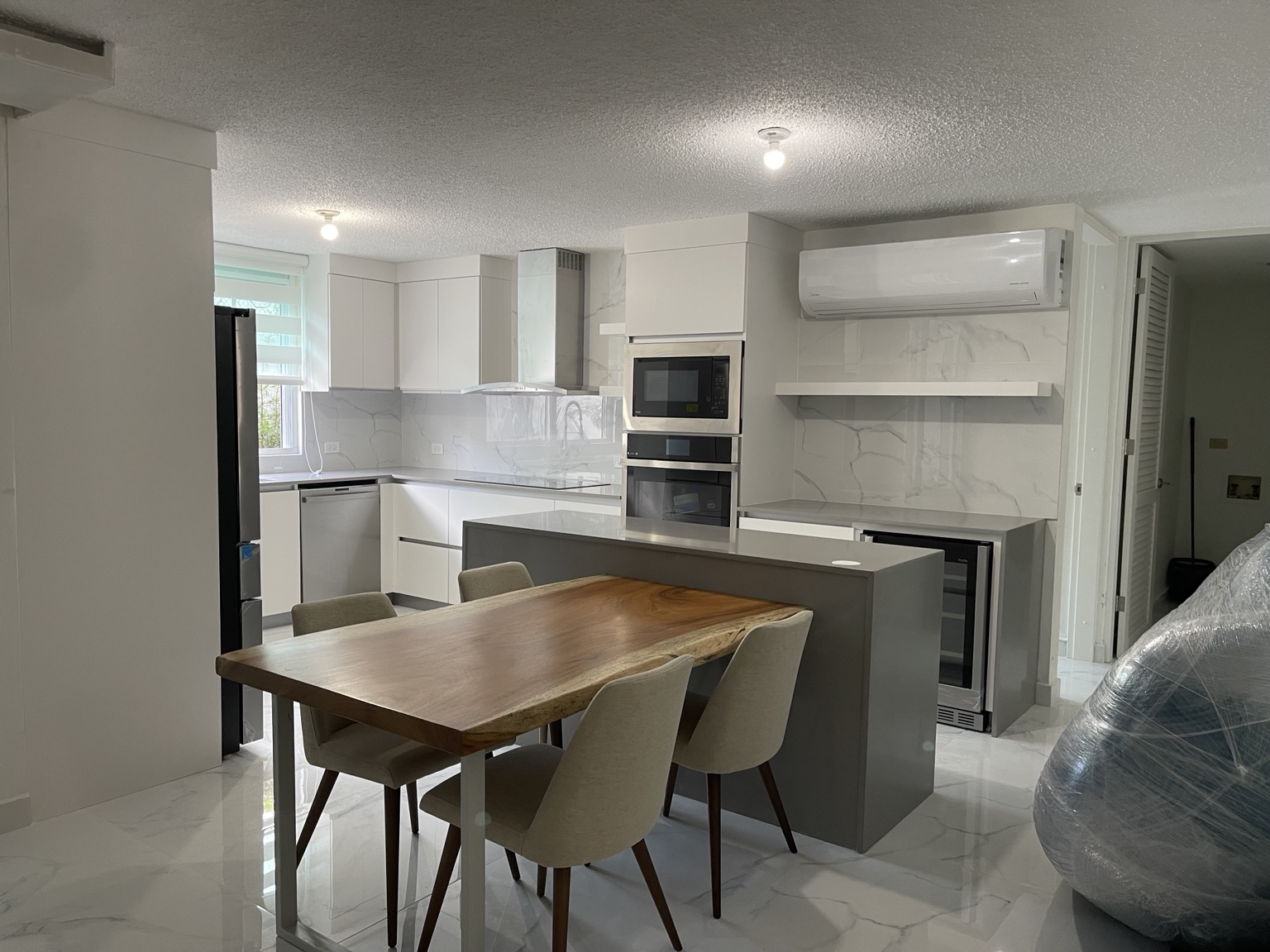 Cocina blanca con isla gris y comedor de madera