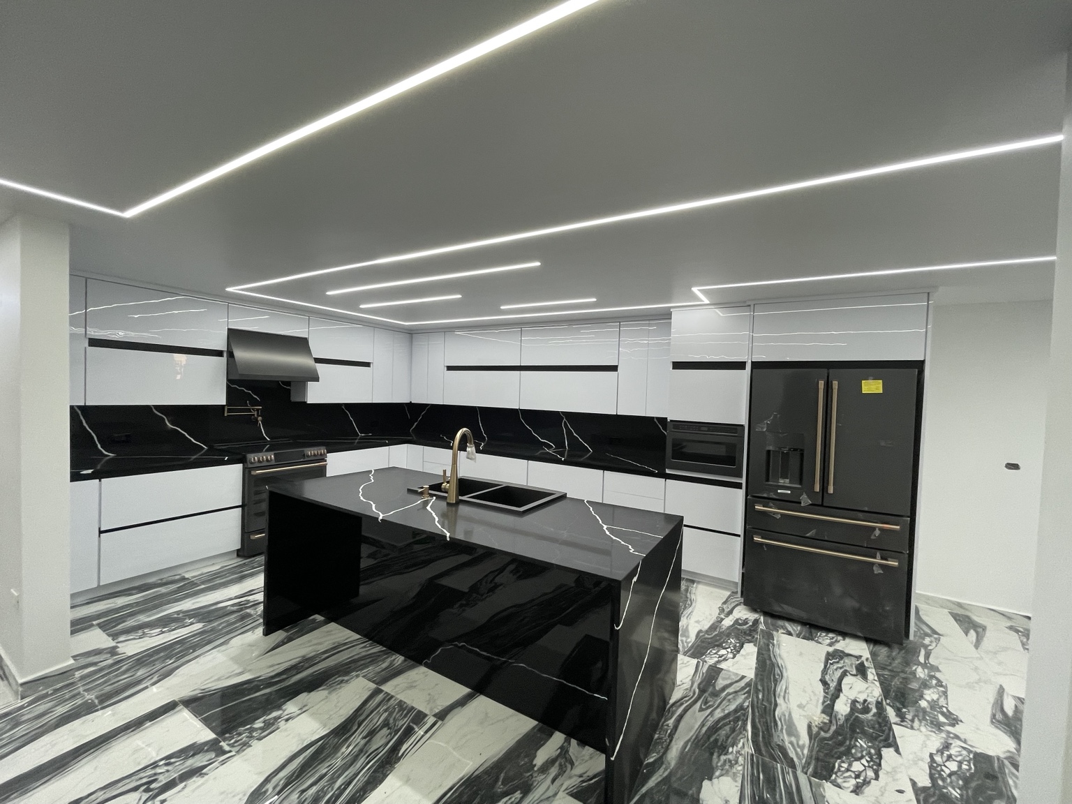 Cocina moderna en blanco y negro con isla, cuarzo e iluminación lineal